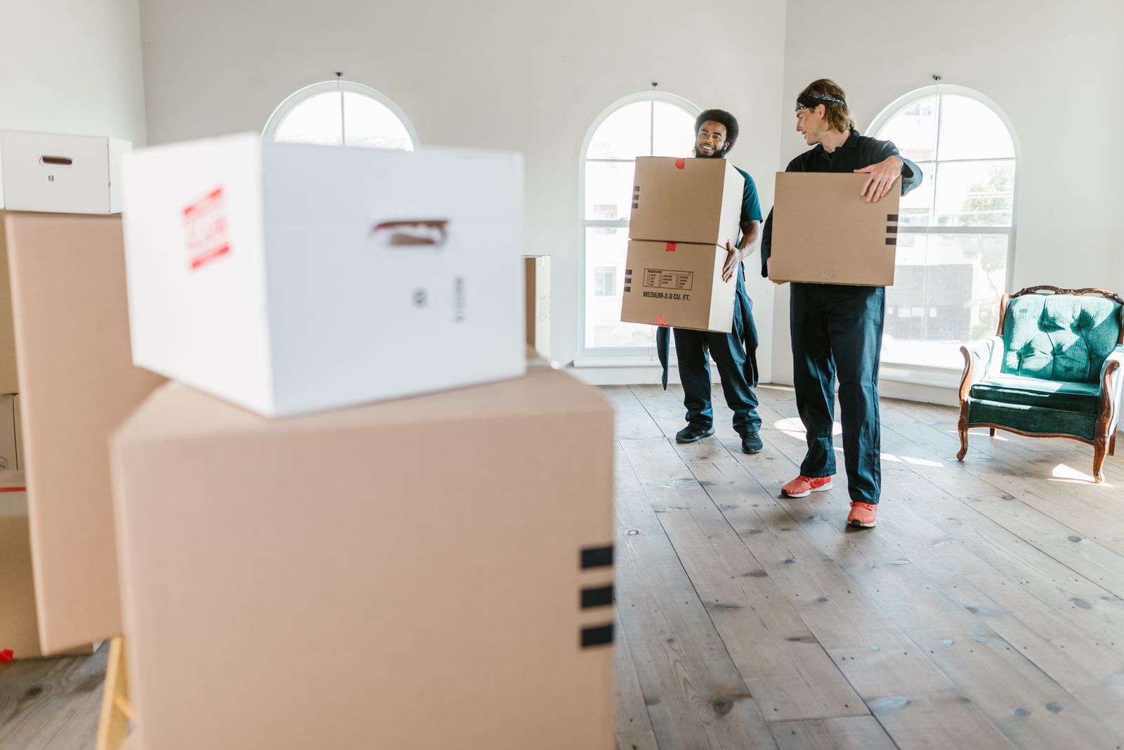 Zwei Umzugshelfer tragen Kartons in eine Wohnung
